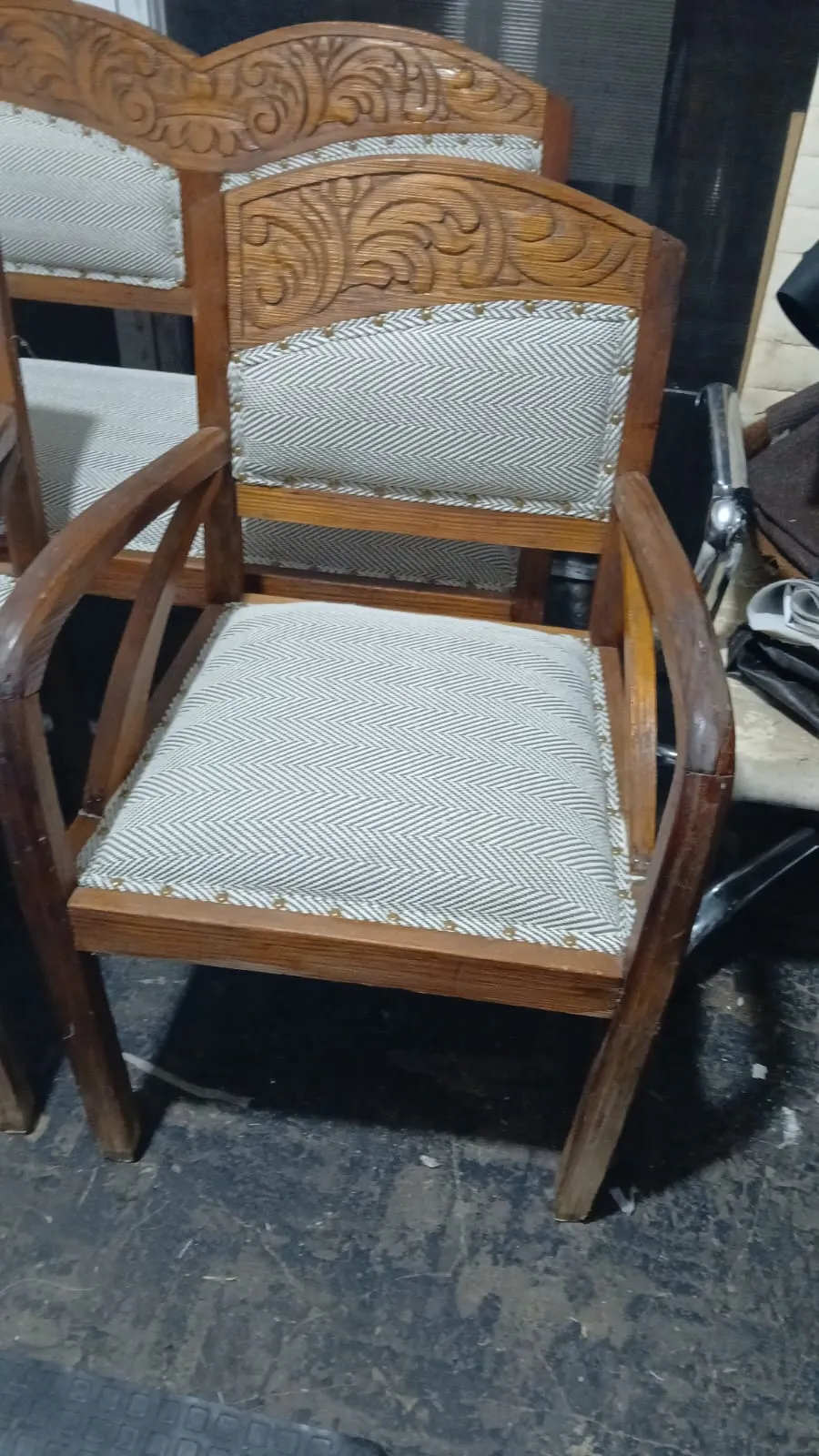Sillón de madera tallada con asiento y respaldo tapizados en tela espiga y tachas